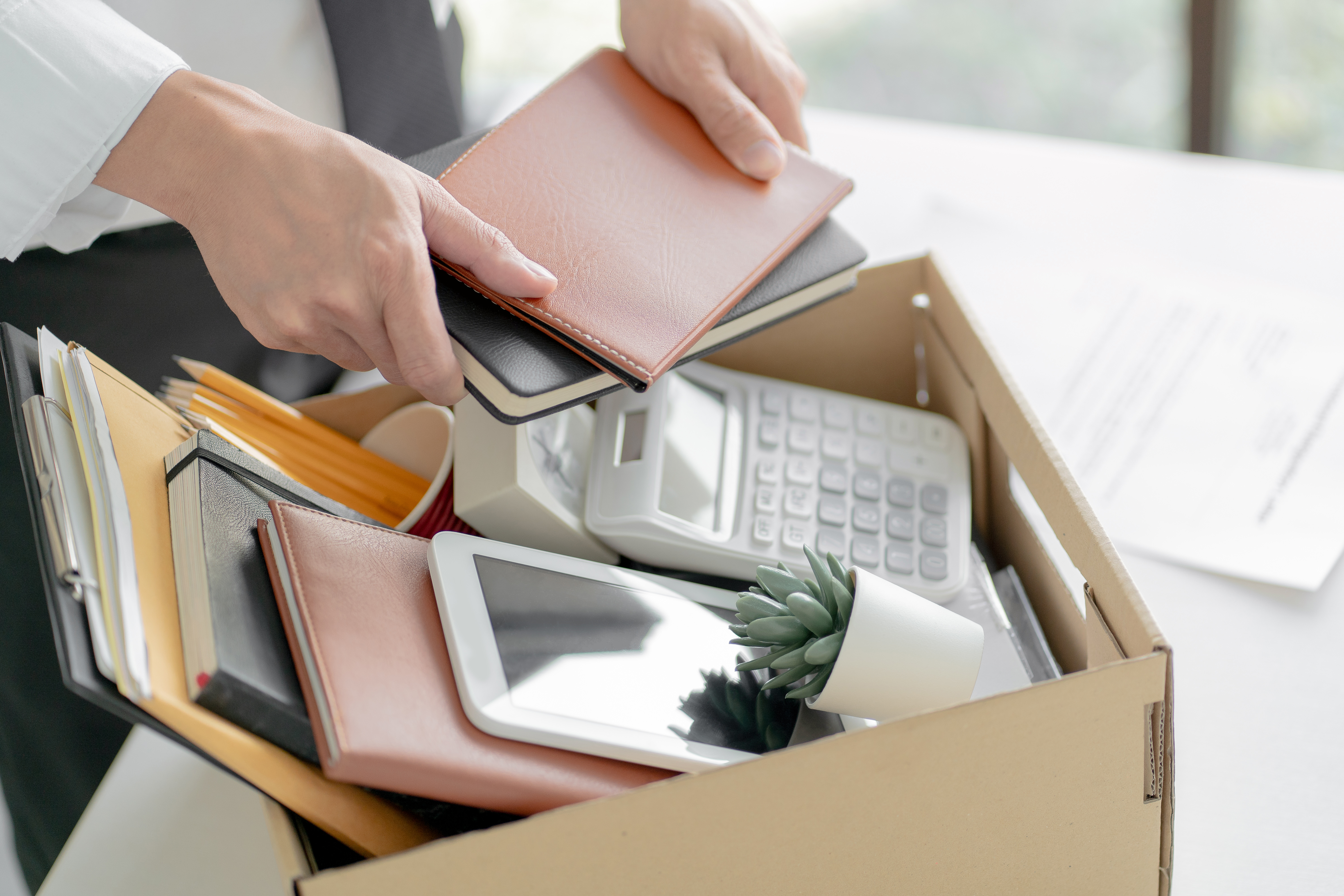 Auf dem Bild ist eine Kiste mit persönlichen Bürogegenständen zu sehen, die gepackt wird