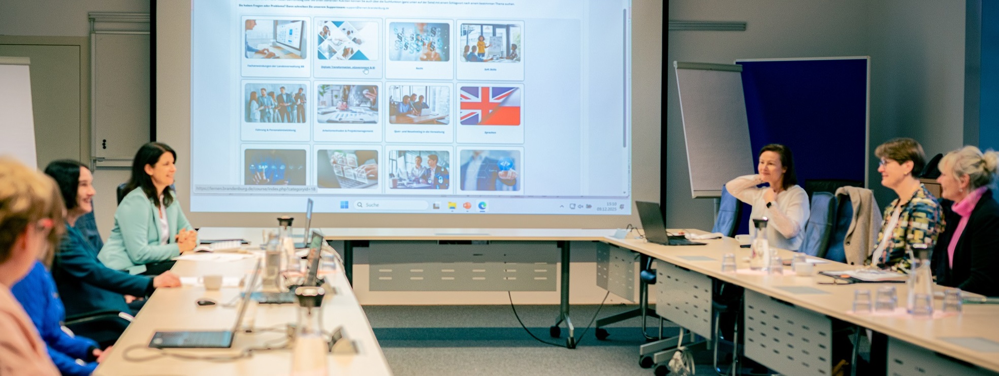 Bild: Projektmeeting der eLeVe-Projektgruppe, einige Projektmitglieder und die an die Wand projezierte Startseite von lernen.brandenburg.de sind abgebildet