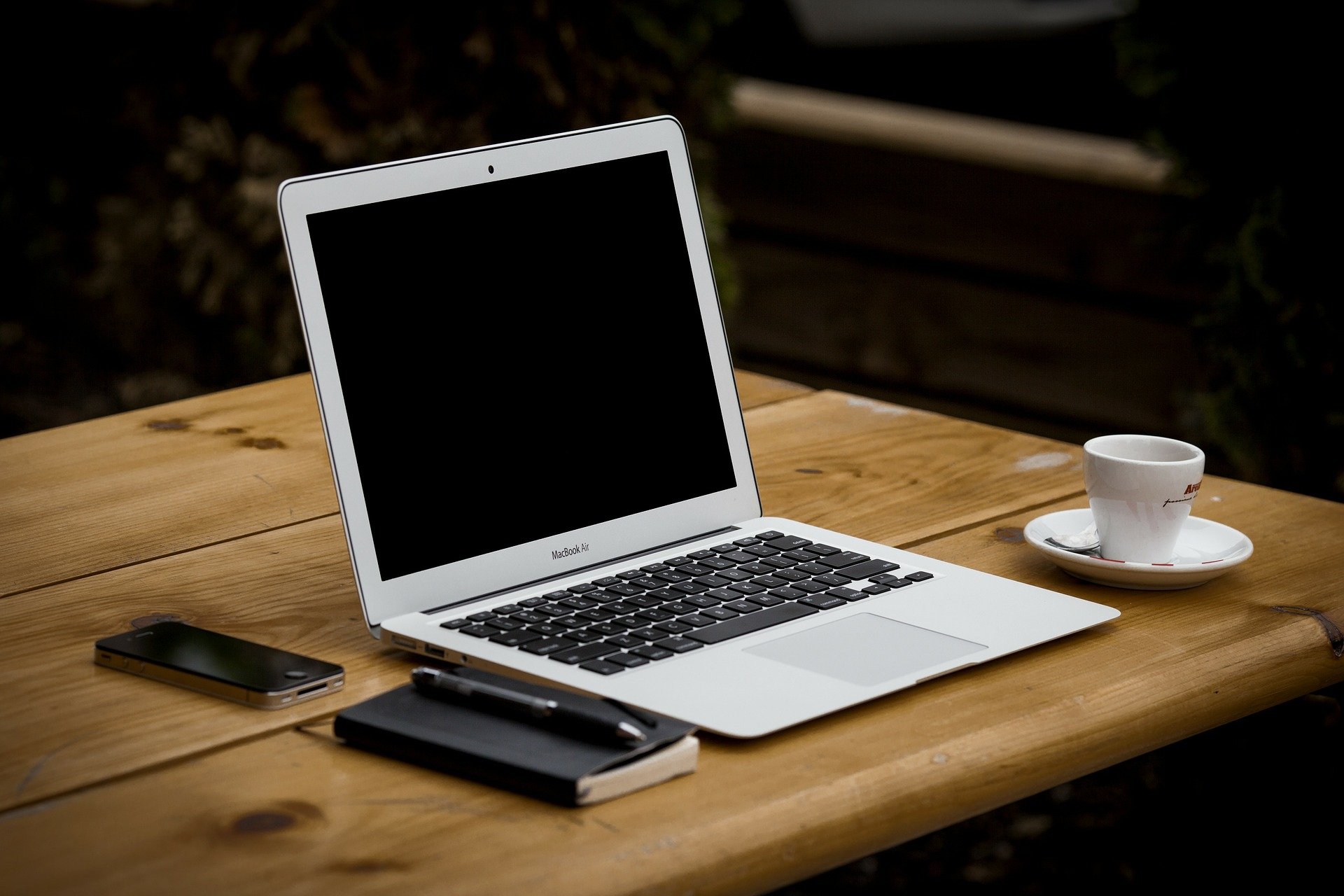 Auf dem Bild iost ein Laptop, eine Kaffeetasse und ein Notizbuch abgebildet