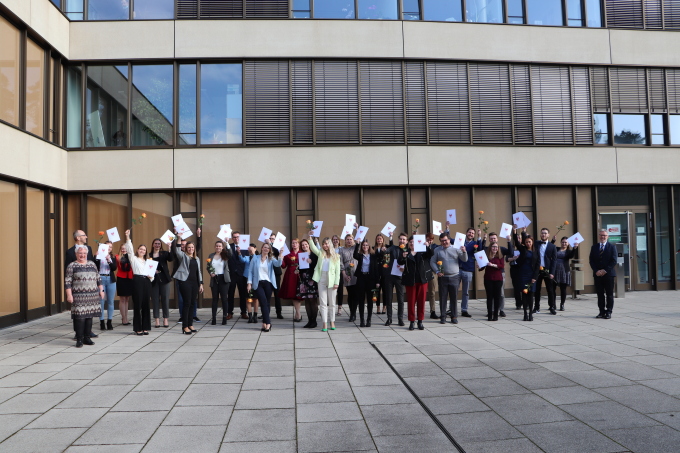Die AbsolventInnen als Gruppe aufgenommen, heben ihre Zeugnisse in die Höhe