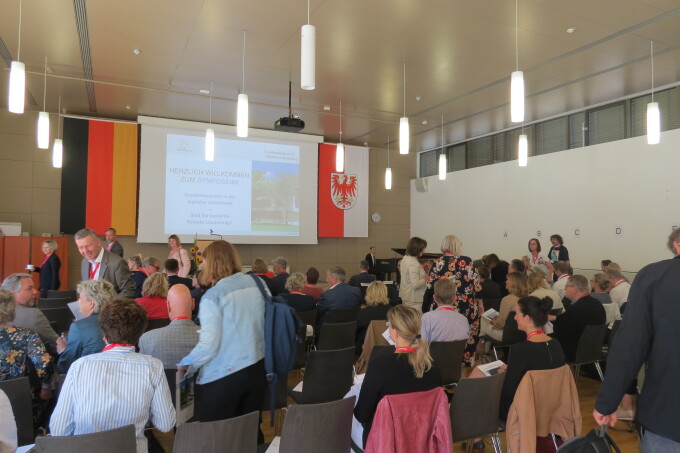 Blick in den Veranstaltungsraum - die Gäste kommen gerade an und setzen sich